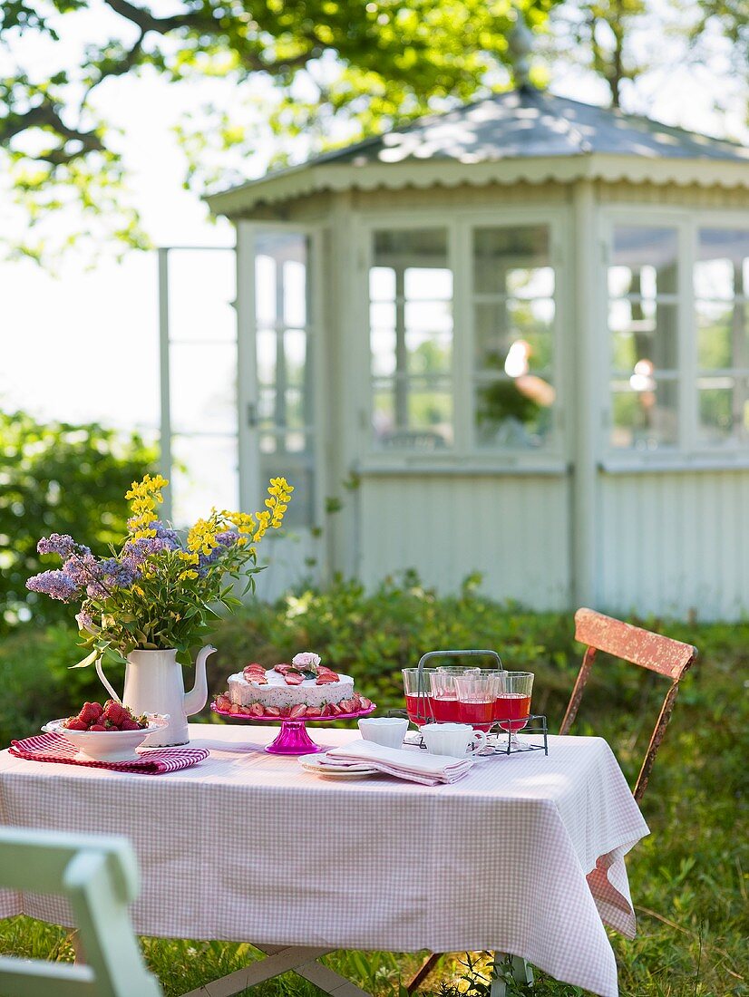 Gedeckter Tisch im Garten, im Hintergrund Gartenpavillion