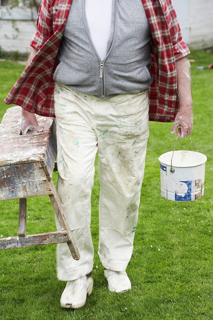 Man carrying painter's bench & paint pot