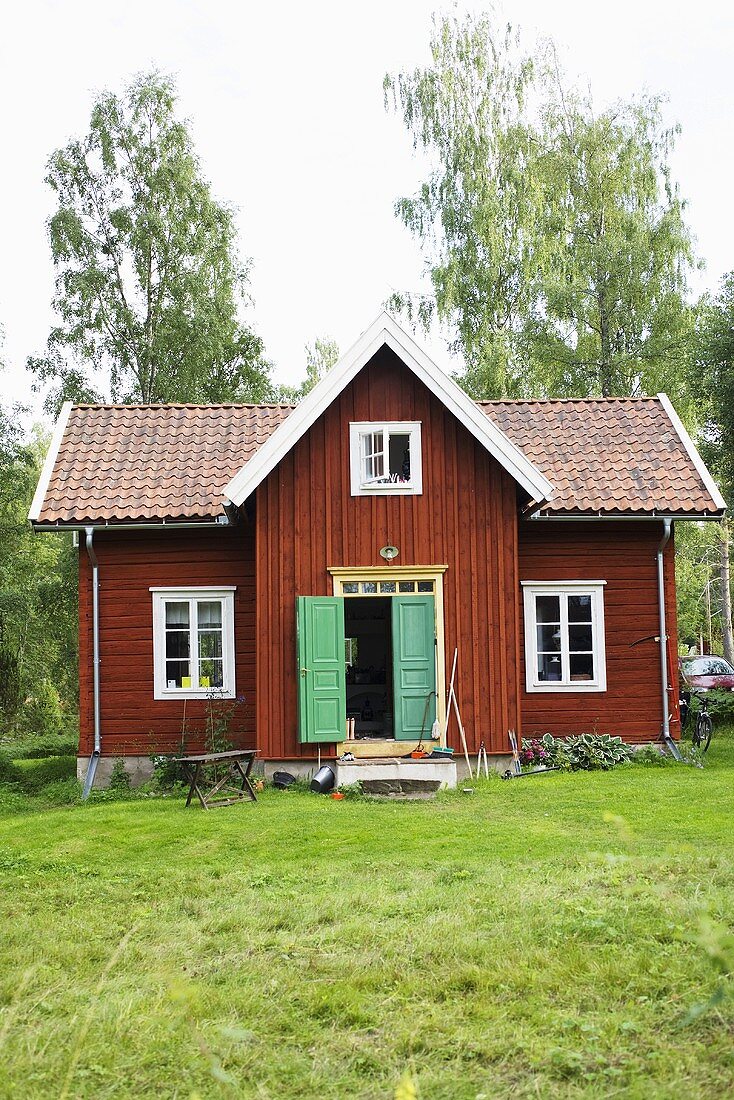 Blick auf kleines braunes Holzhaus mit geöffneter Eingangstür