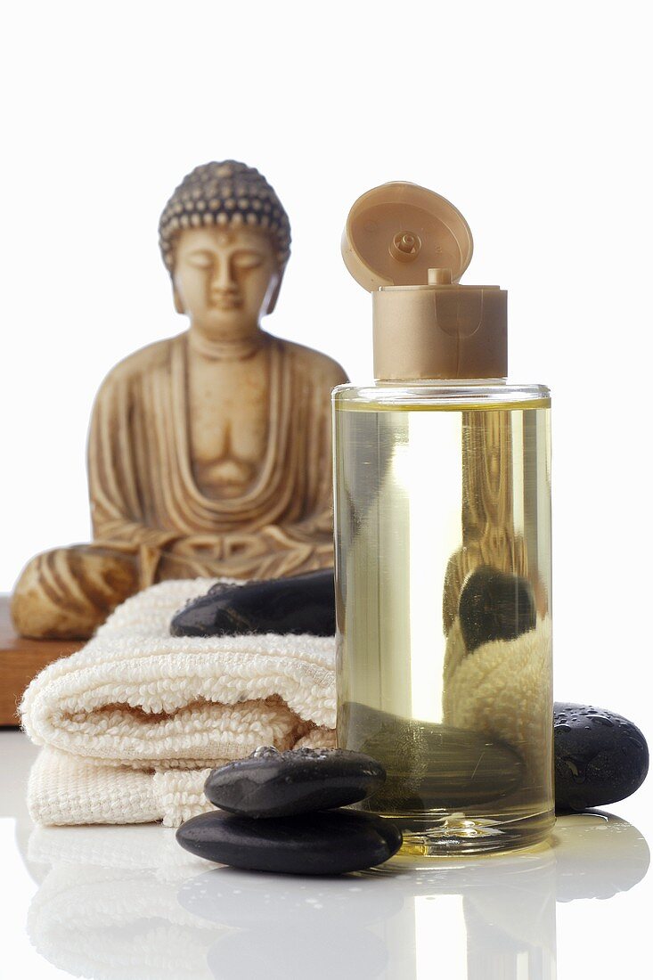 Massageöl und Warmsteine, Buddhafigur im Hintergrund