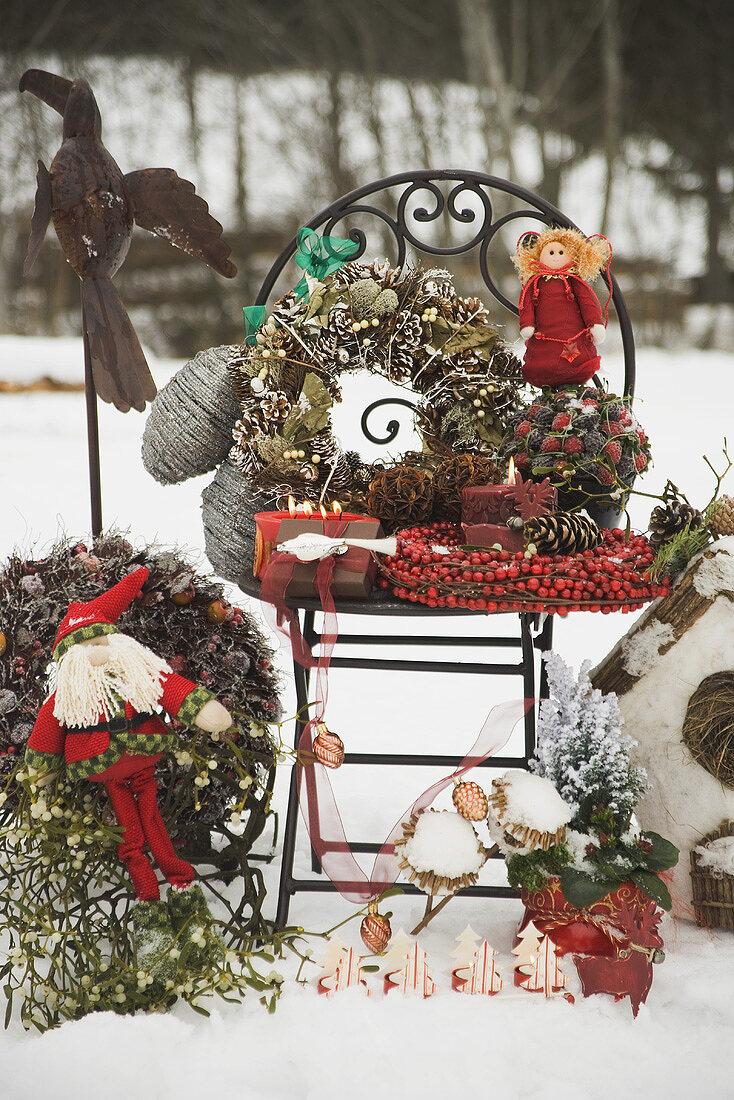 Weihnachtsdeko auf Gartenstuhl im Schnee