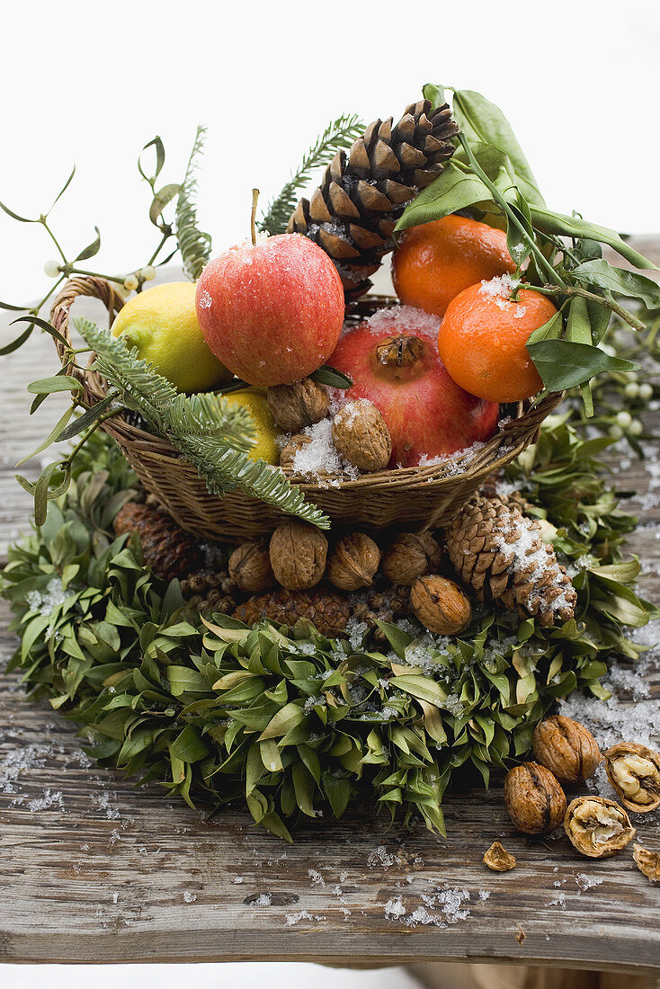 Weihnachtsdeko mit Obst, Nüssen, Zapfen und Buchsbaumkranz