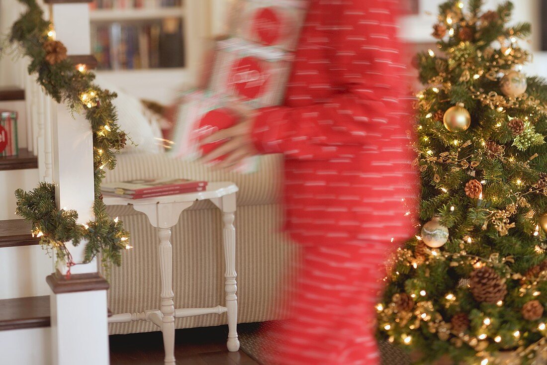 Woman carrying boxes of Christmas decorations through living room