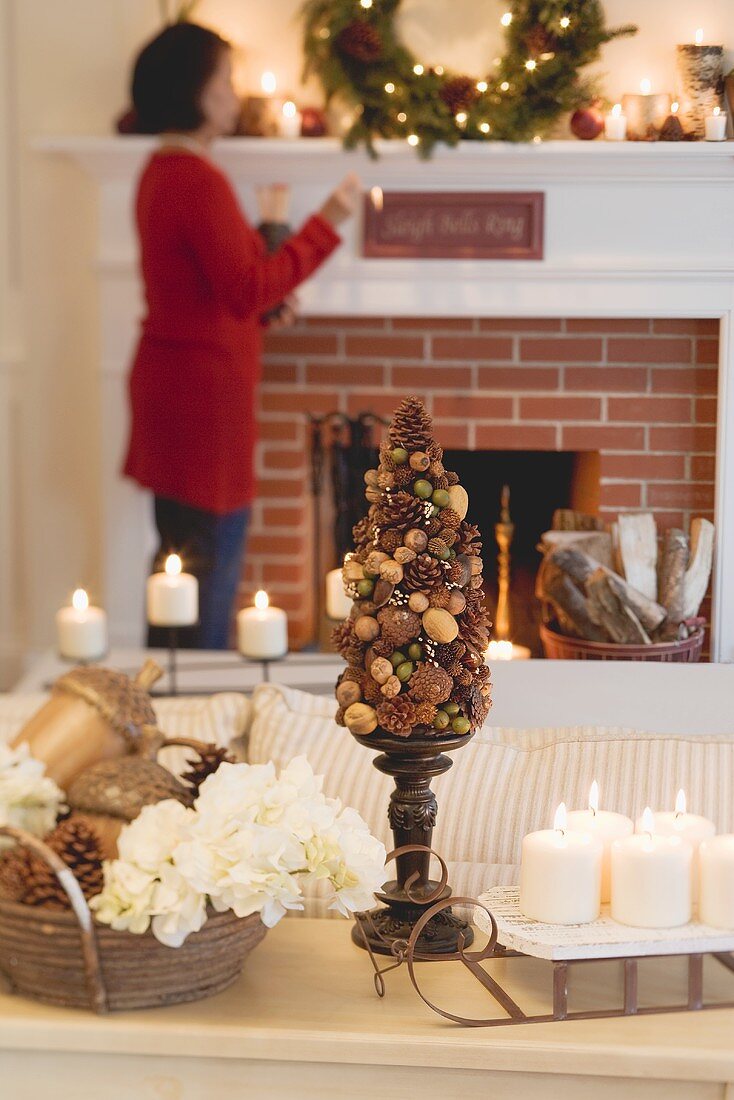 Frau am Kamin im weihnachtlich dekorierten Wohnzimmer