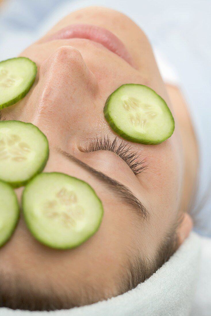 Woman with slices of fresh cucumber on her face