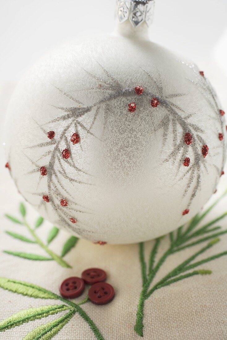 White Christmas tree bauble on embroidered linen cloth