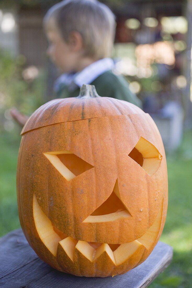 Geschnitztes Kürbisgesicht für Halloween, Kind im Hintergrund