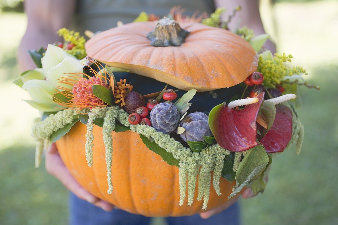 Man holding pumpkin decorated with flowers
