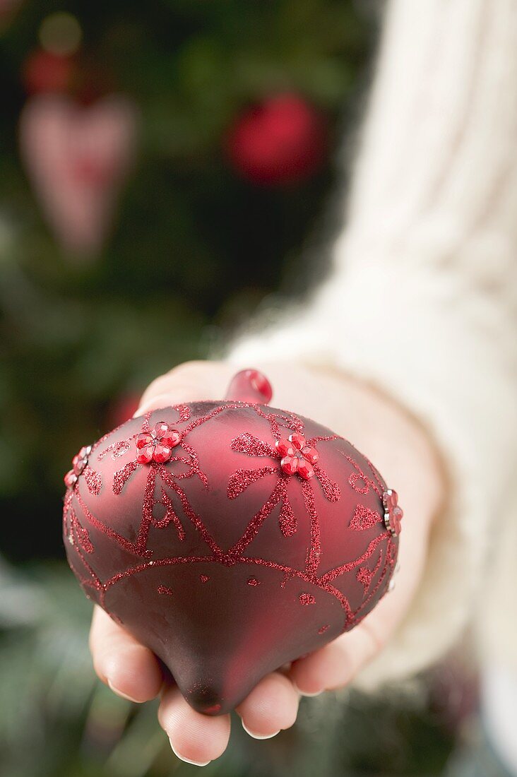 Hand holding red Christmas bauble