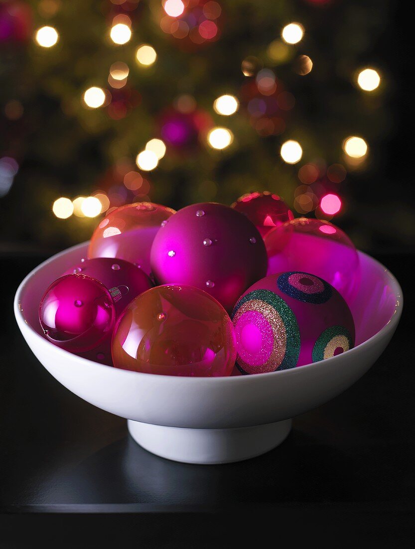 Bowl of Christmas baubles, Christmas tree in background