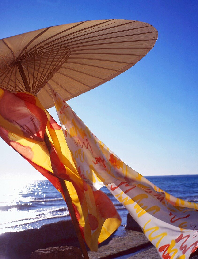 Sonnenschirm mit bunten Tüchern am Meer