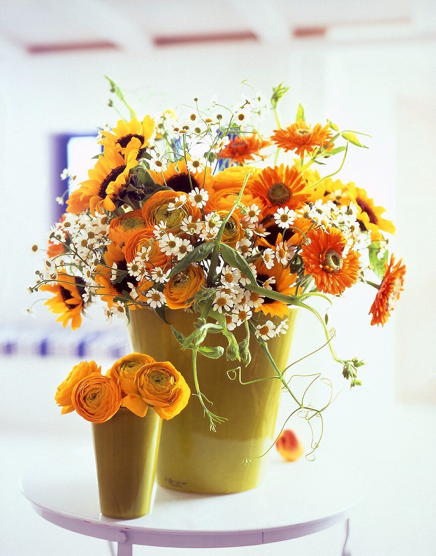 Chamomile, ranunculus, sunflowers and marigolds in vases
