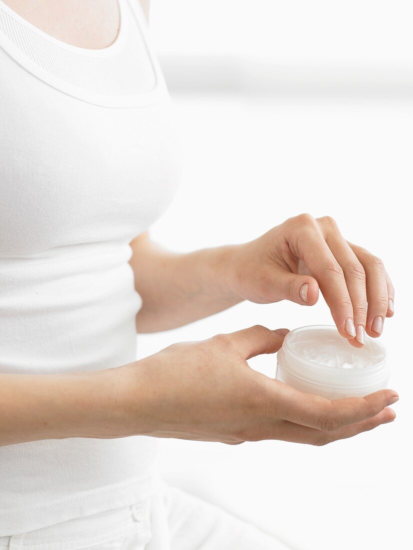 Woman holding pot of skin cream