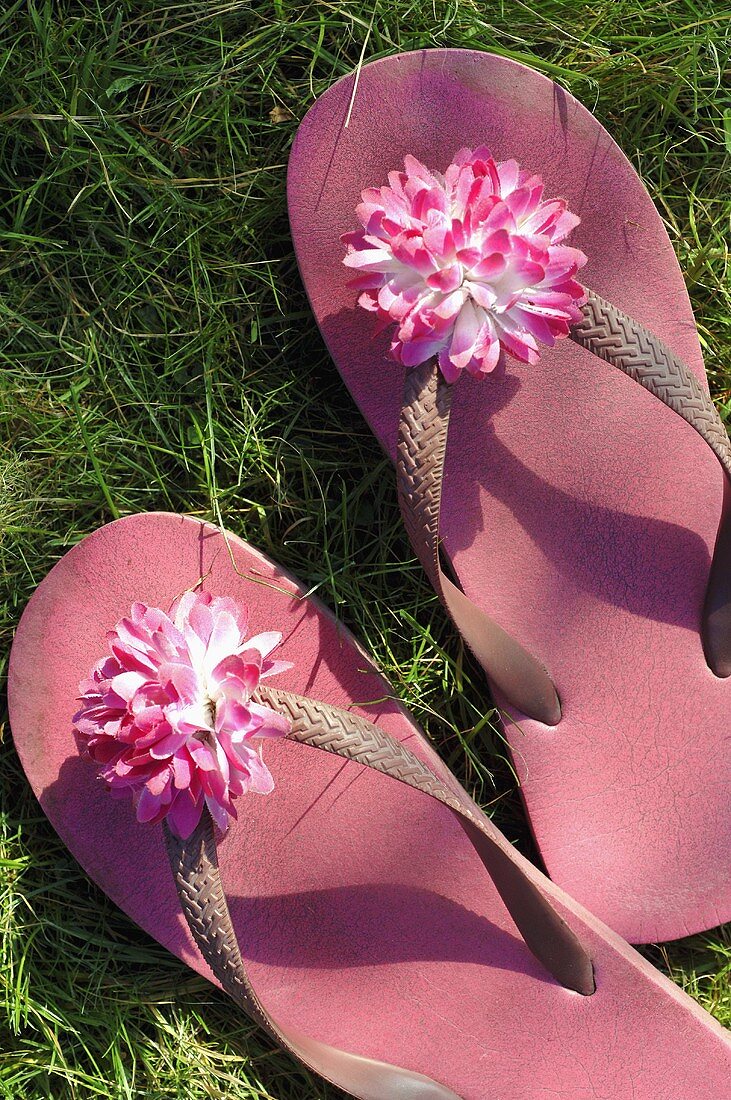 Pink flip-flops with flowers on grass
