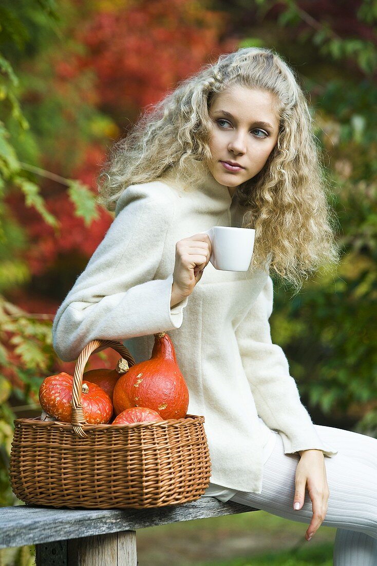 Young woman with basket and cup in park in autumn
