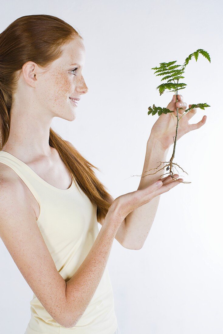 Junge Frau hält grüne Pflanze in der Hand