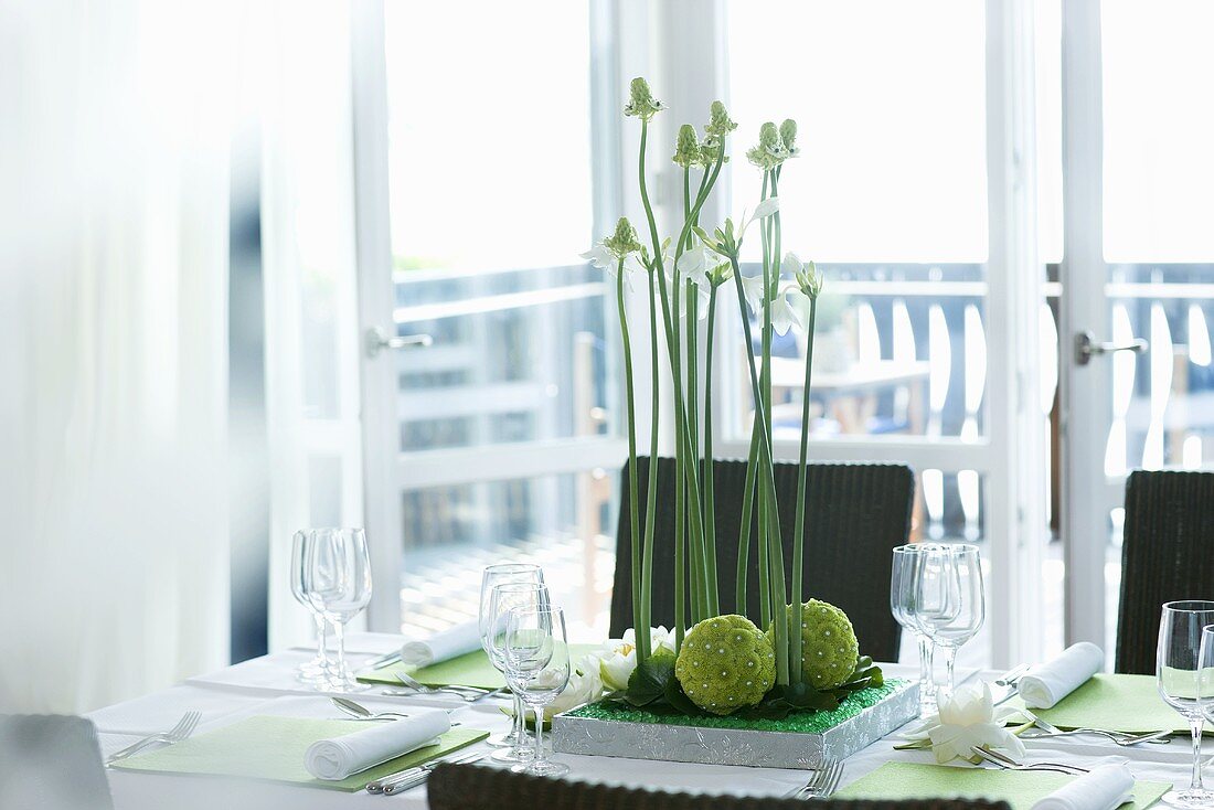 Gedeckter Esstisch mit Blumengesteck vor hellem Balkon