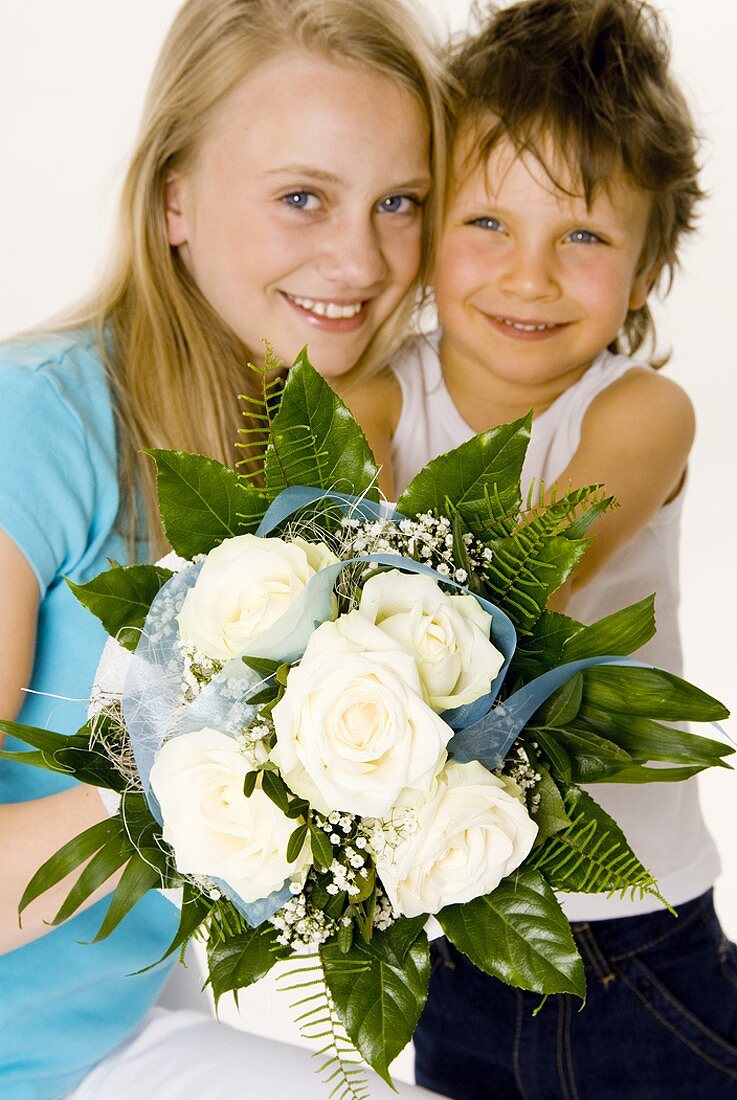 Boy and girl holding bouquet of white roses