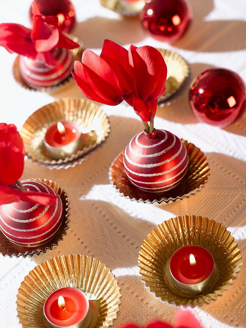 Table decorations: red tealights, cyclamen, Christmas baubles