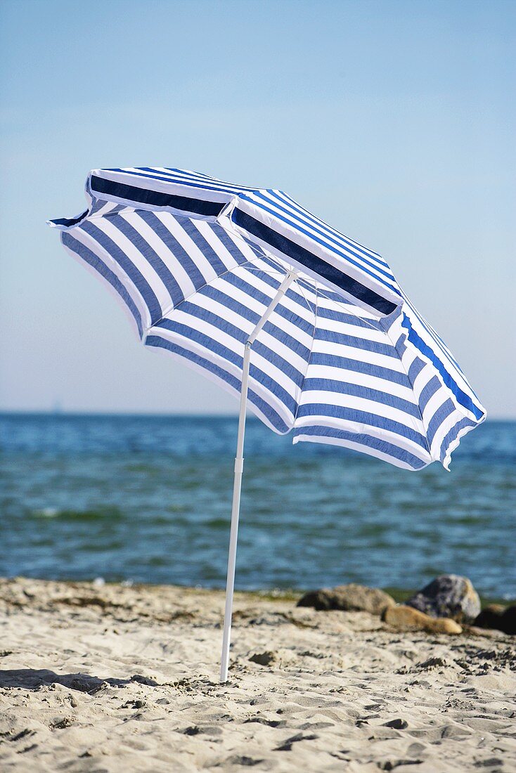 Blue and white beach umbrella by the sea