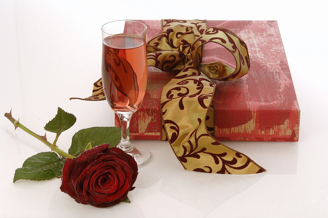 Geschenk, rote Rose und Sektglas