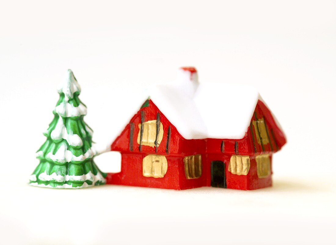 Christmas decorations: red house and snow-covered fir tree