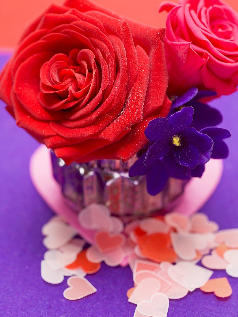 Rote Rosen mit Veilchen in Vase, Papierherzen
