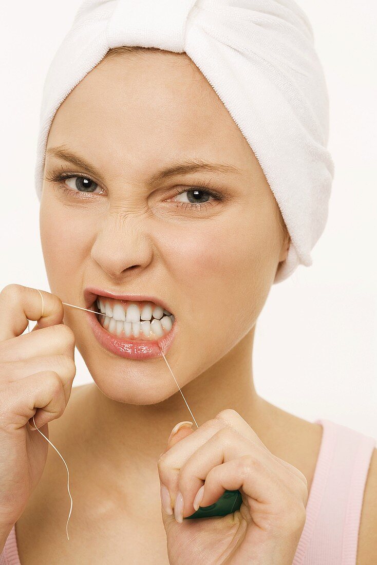 Frau reinigt sich die Zähne mit Zahnseide