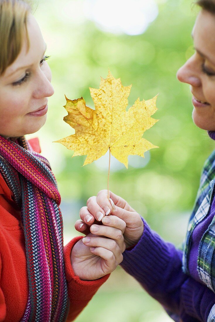 Mother and daughter holding an autumn leaf