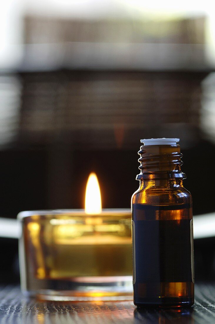Bottle of scented oil, beside a tealight, close-up