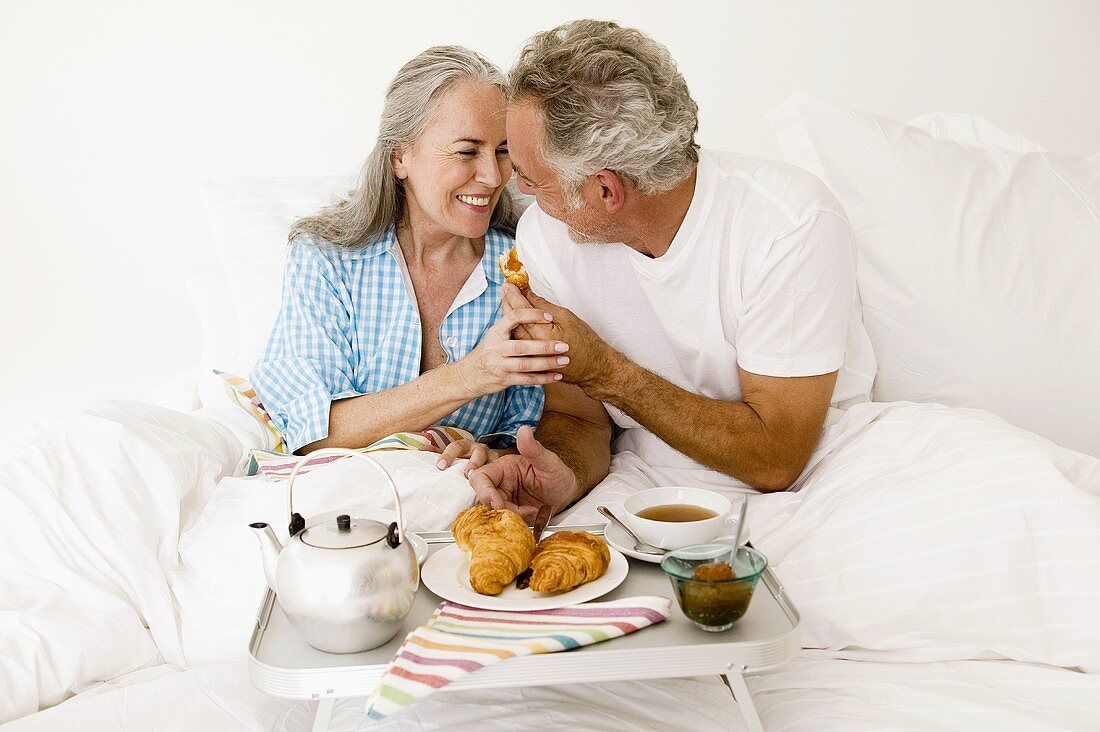 Älteres Ehepaar frühstückt im Bett