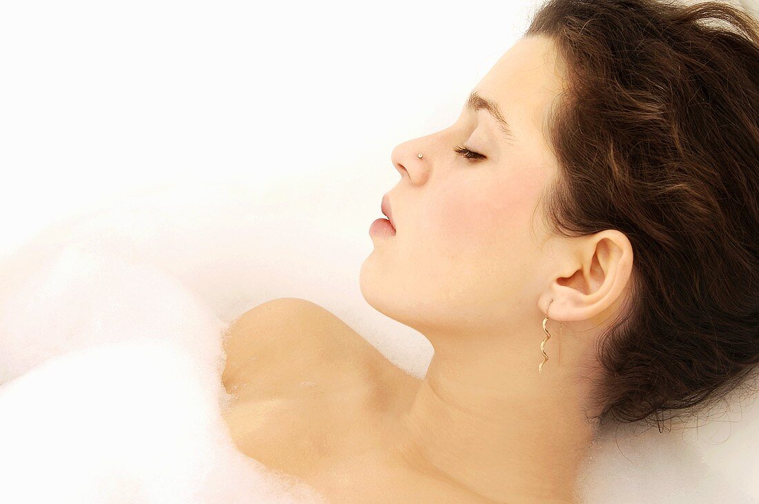 Young woman relaxing in bubble bath, close-up