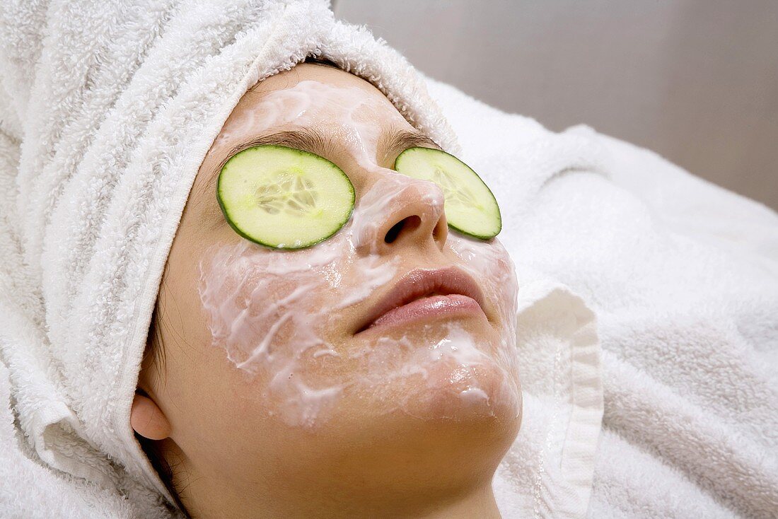Young woman with face mask and cucumber slices