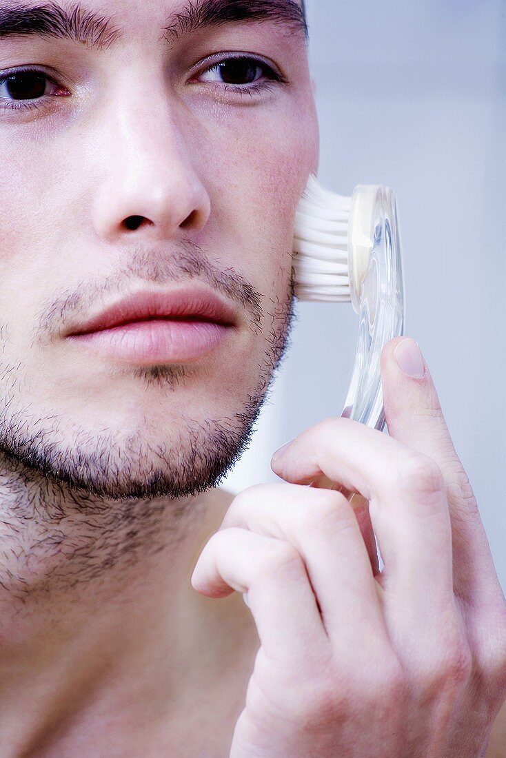 Mann massiert sein Gesicht mit Bürste
