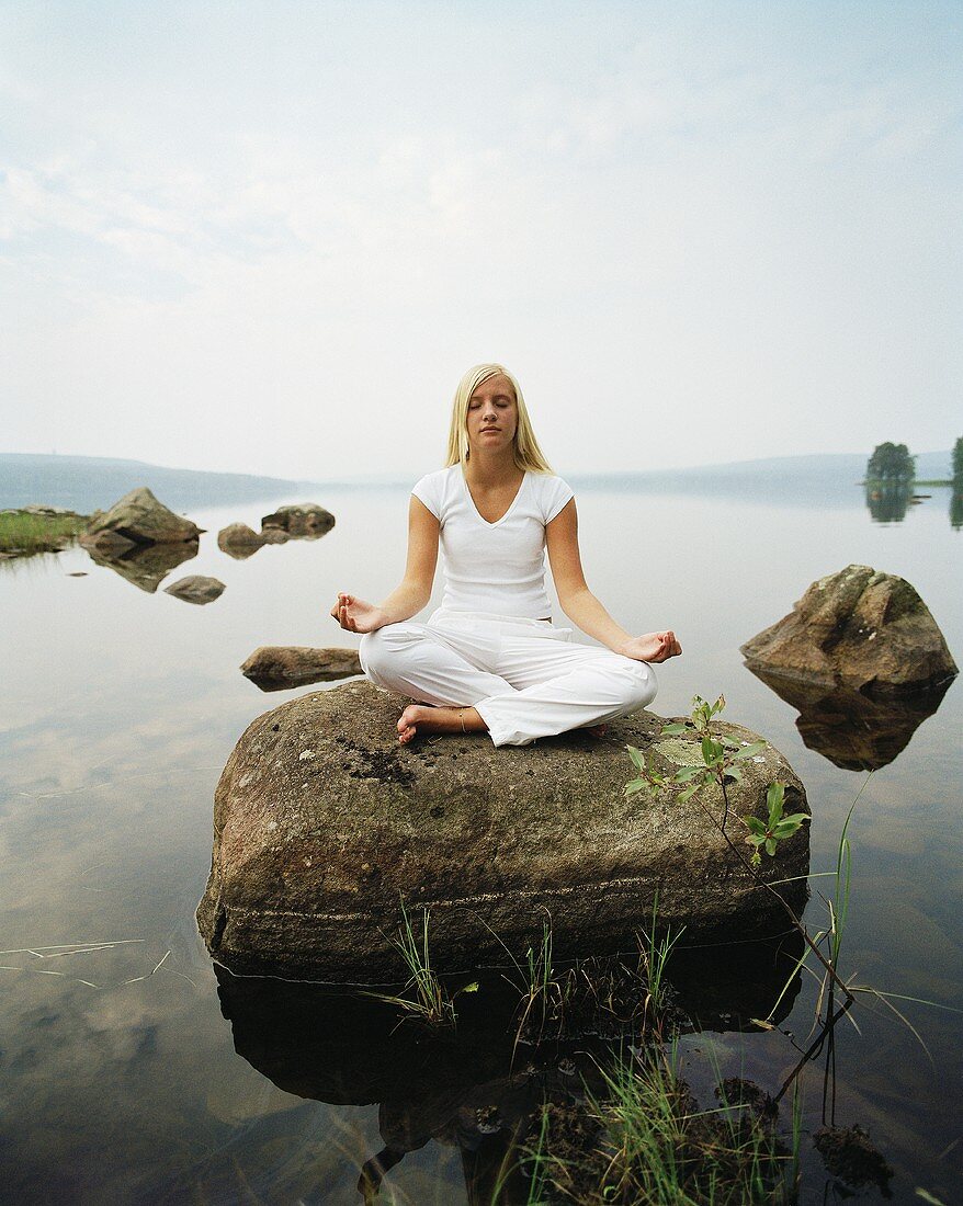 Junge Frau beim Yoga auf einem Stein