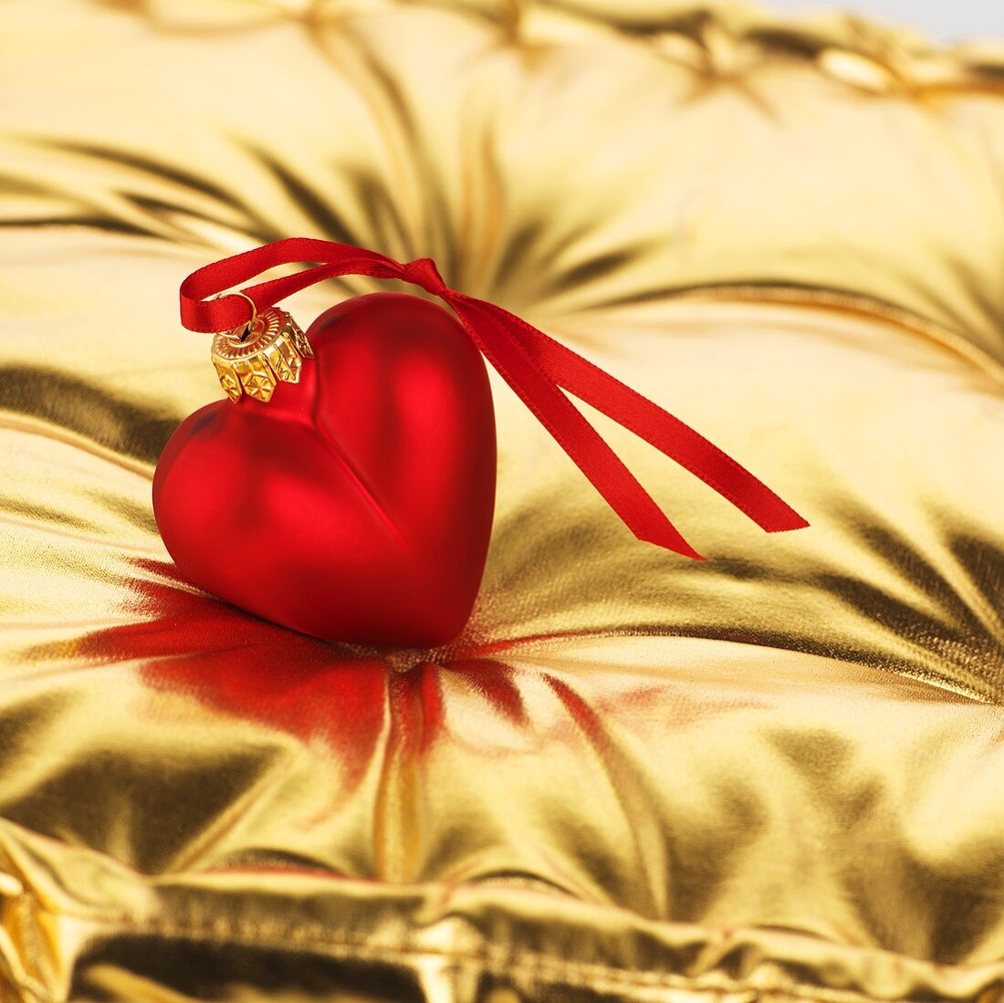 Red heart (tree ornament) on gold cushion