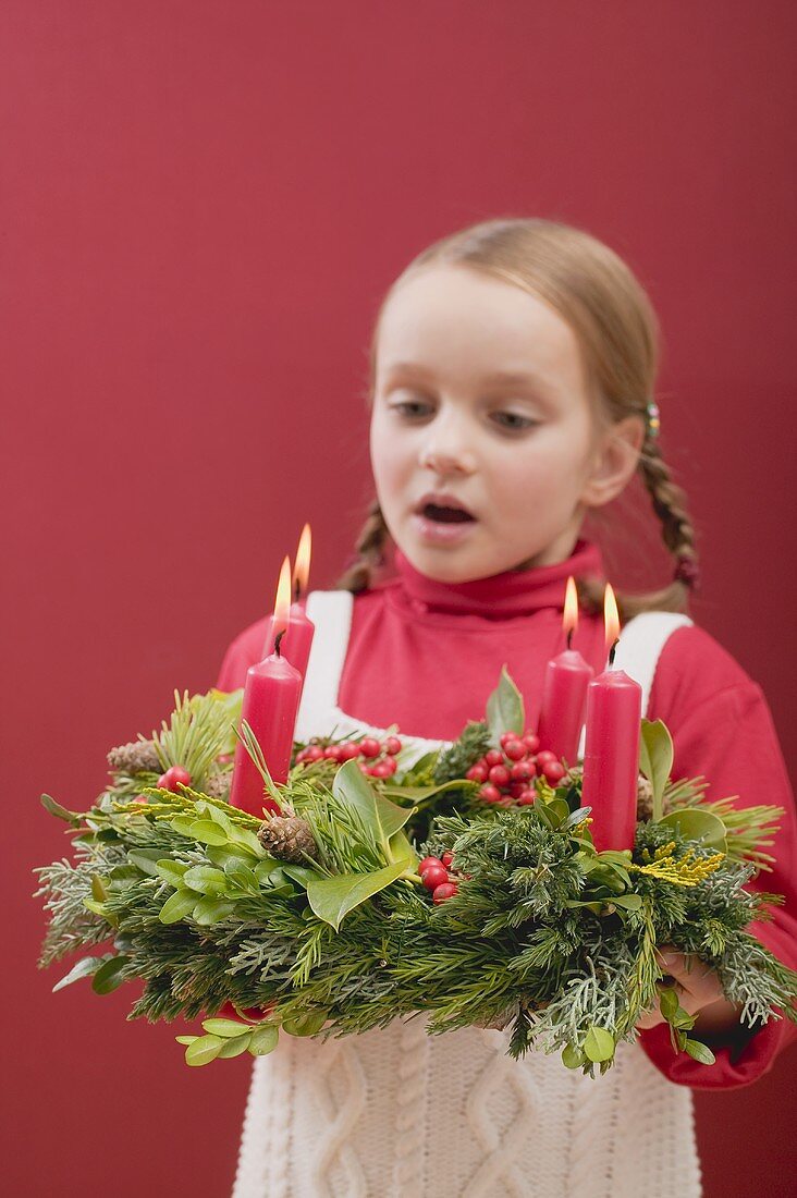 Kleines Mädchen bläst Kerzen am Adventskranz aus