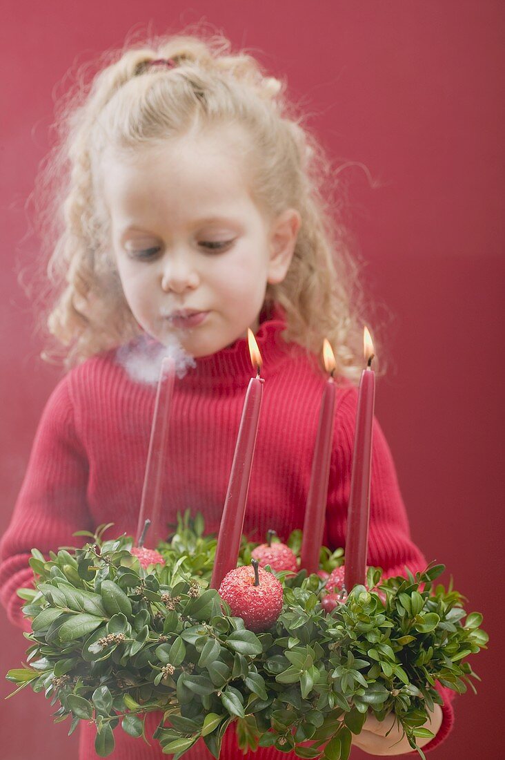 Small girl blowing out candles on Advent wreath