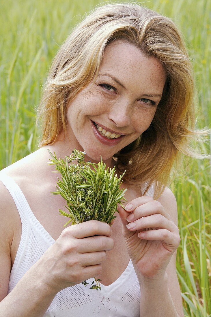 Woman with a bunch of herbs in a meadow