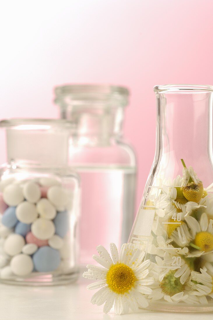 Kamillenblüten und Tabletten in Apothekerflaschen