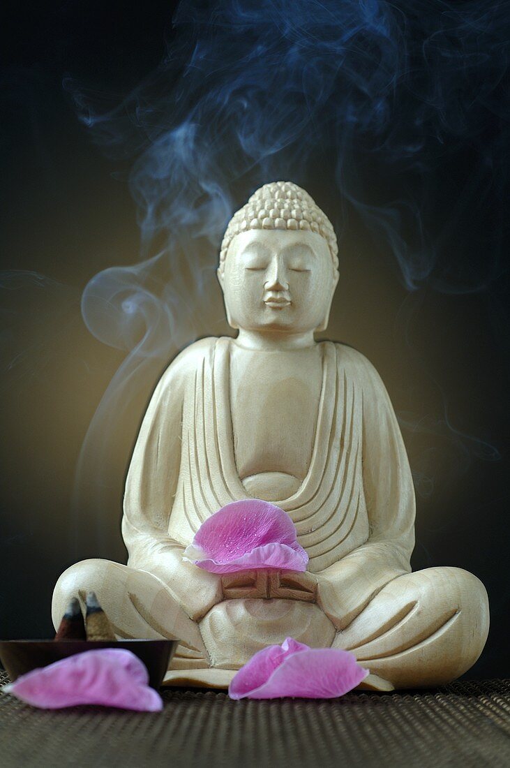 Buddhafigur mit Räucherstäbchen und Blütenblättern
