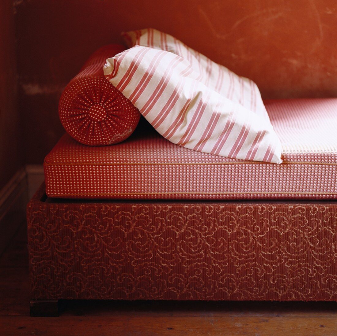 Oranges Bett mit Streifen- und Karomuster; den Bettkasten ziert ein florales Motiv