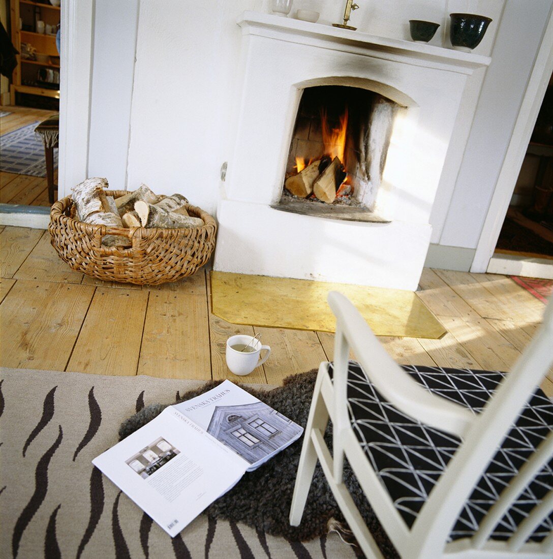 Gemütlicher Platz am offenen Kamin mit aufgeschlagenem Buch und einer Tasse Tee