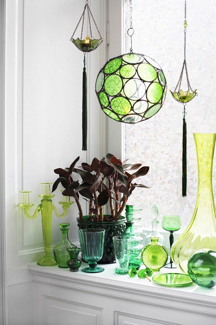 Potted plant, candlestick, vases and glasses by window