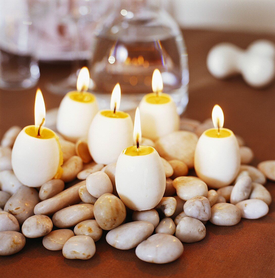 Egg-shaped candles on pebbles