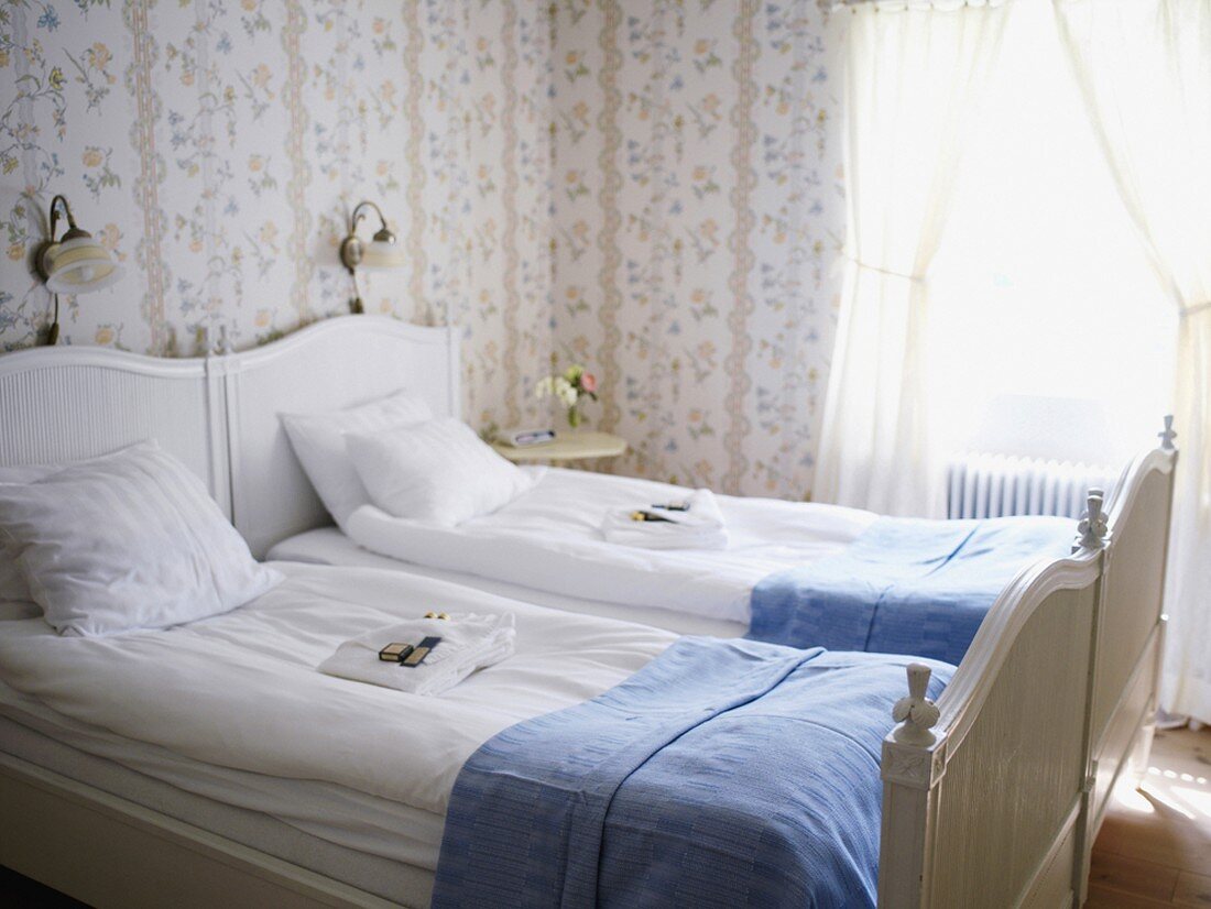 Romantisches Schlafzimmer mit weißem Doppelbett und Blümchentapete
