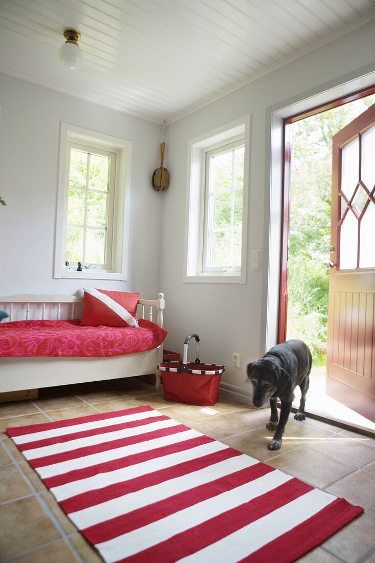 Vorraum eines schwedischen Landhauses mit weiss-roten Akzenten und mit eintretendem Hund