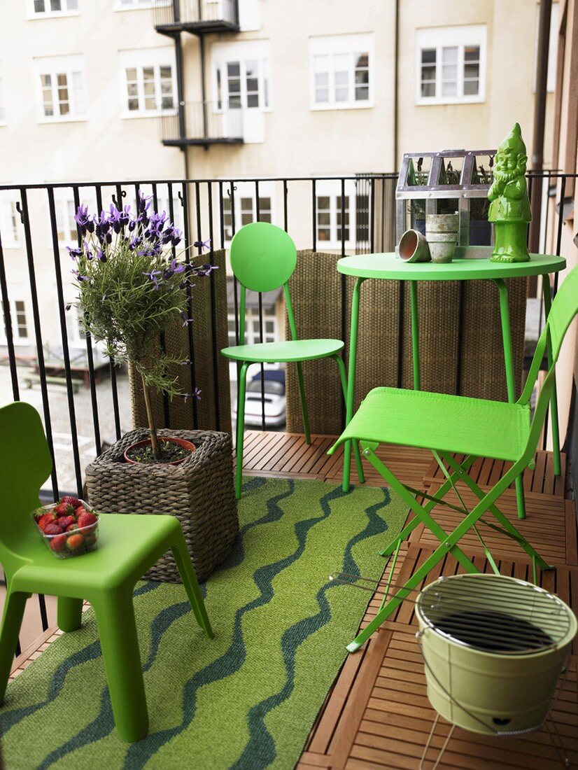 Balkon einer Stadtwohnung mit grünen Balkonmöbeln, Topfpflanze und grünem Gartenzwerg