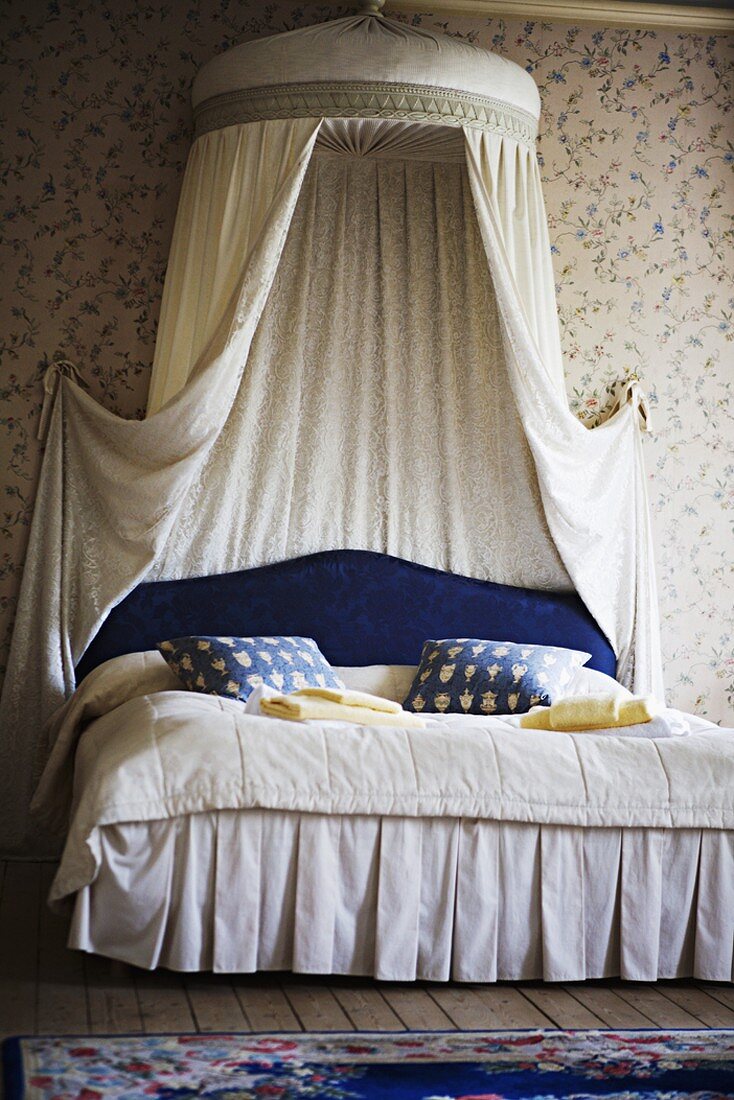 Romantisches Schlafzimmer mit Blümchentapete und großem Doppelbett mit fürstlichem Baldachin