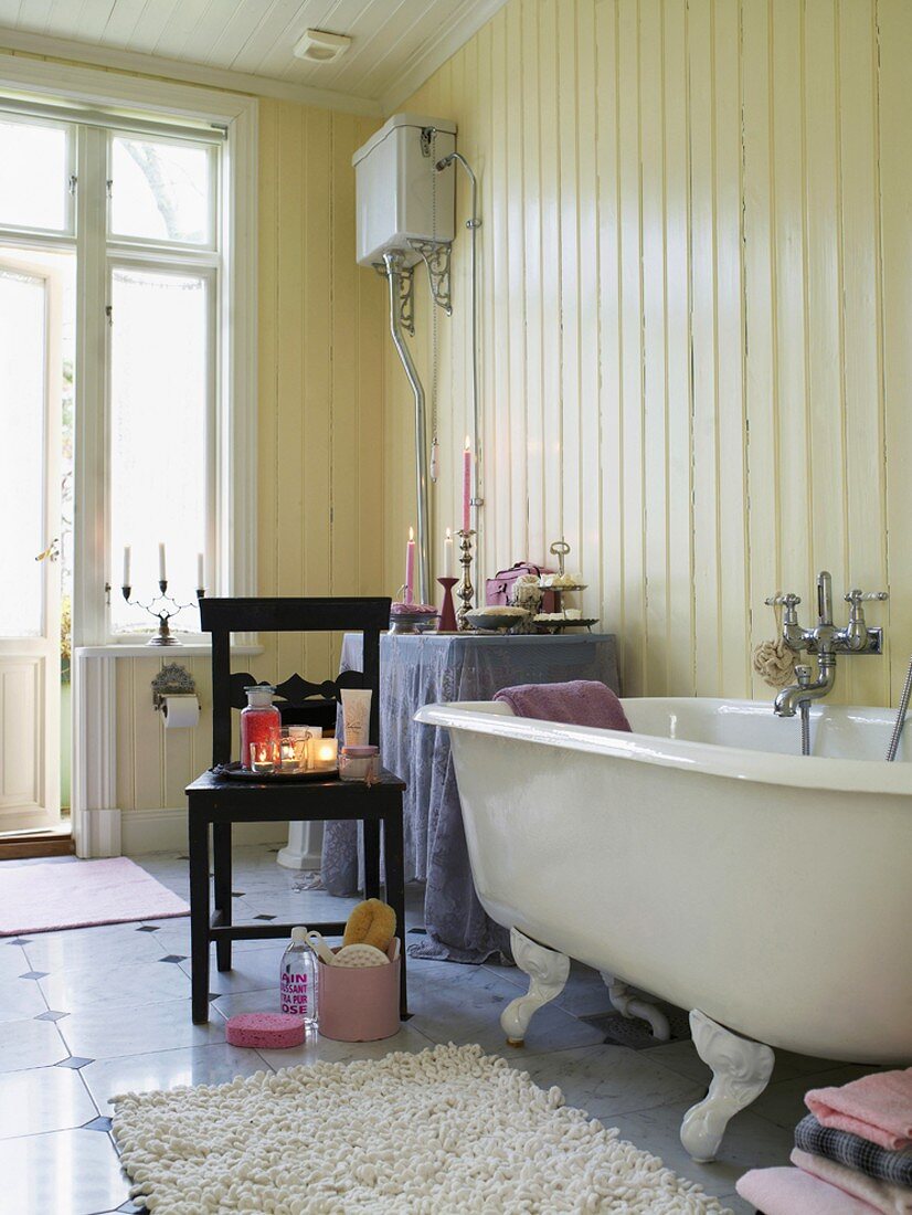 Traditionelles Badezimmer mit freistehender Badewanne, holzverkleideten Wänden und Steinfliesen